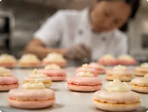 Jenna in her kitchen behind trays of filled macarons